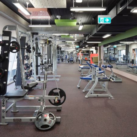 A man looking into a gym mirror while working out among fitness equipment. Are the many mirrors in gyms actually bad for exercising?