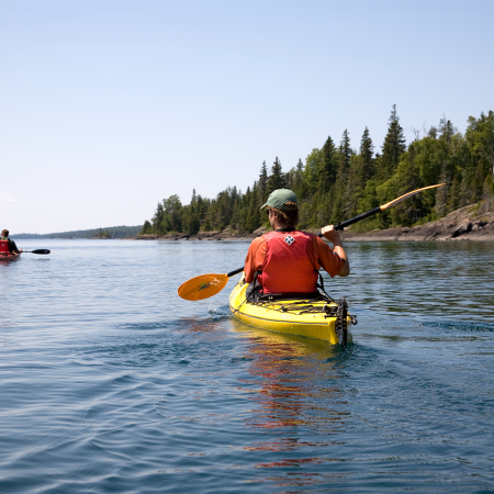 Two people kayaking off the shore of Isle Royale National Park, one of five parks along Lake Superior that plans to decarbonize in order to fight climate change