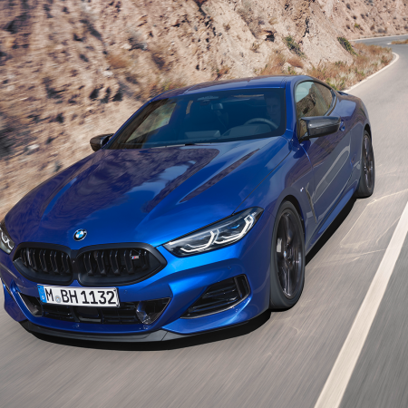 A blue 2023 BMW M850i Coupe, part of the BMW 8 Series, driving down the road. Read our full review of the luxury coupe.