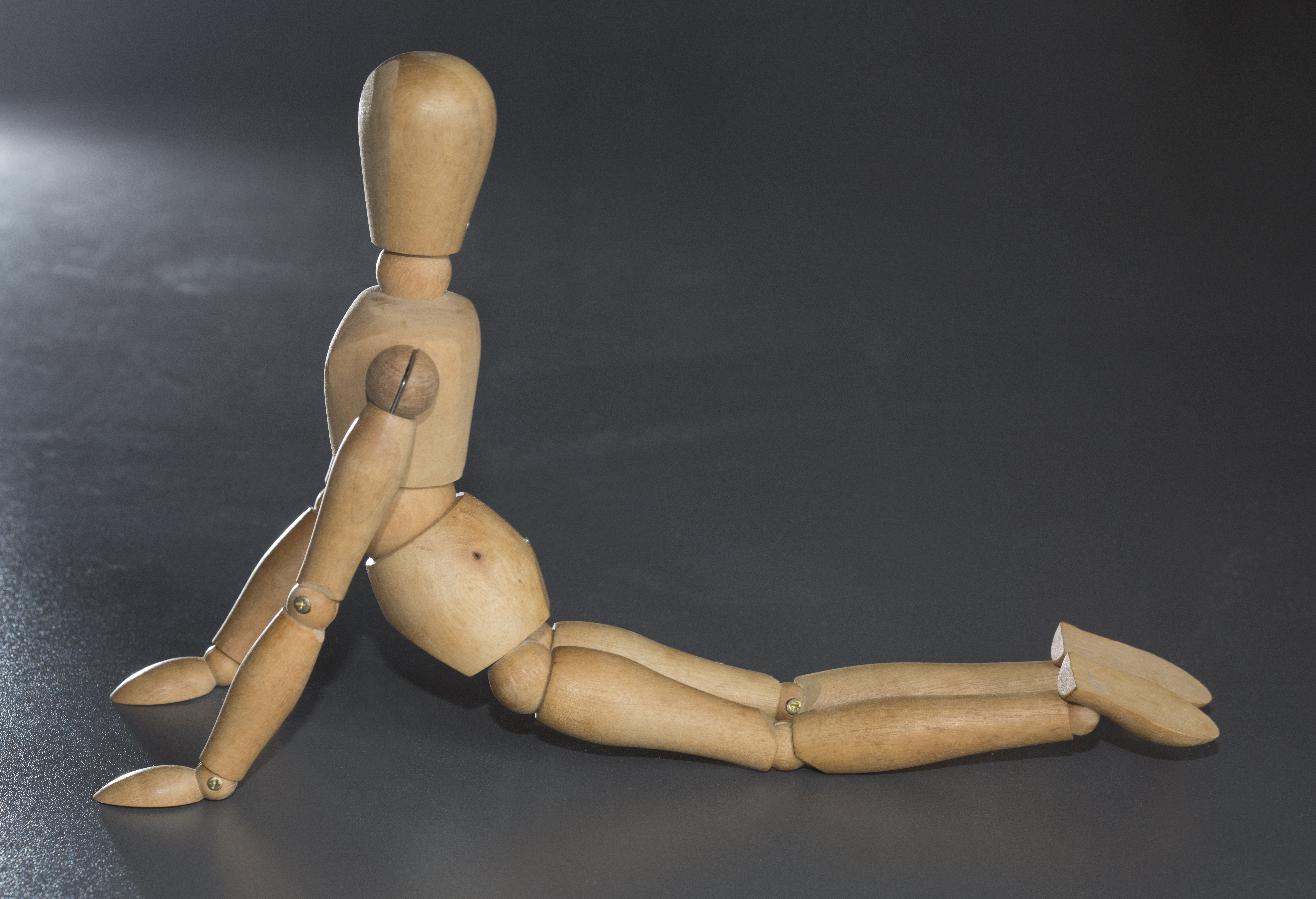 A wooden puppet stretching on the floor