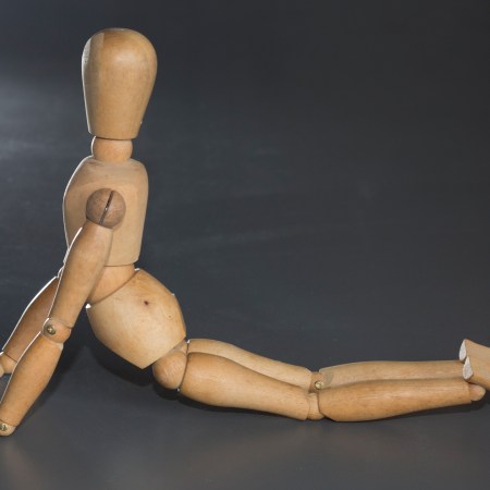 A wooden puppet stretching on the floor