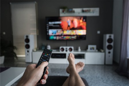 A young man is browsing through television channels with a remote control. Figuring out your home theater sound system isn't as daunting as it sounds - we explain the difference between 5.1, 7.1, Dolby Atmos and more