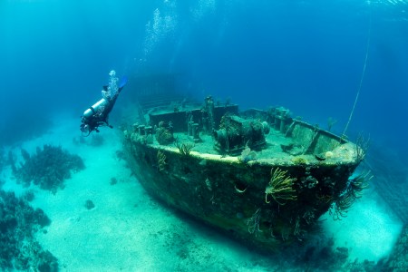 Scuba Diver Exploring a Large Shipwreck in the bahamas. A sunken treasure of booze and gold is planning to be excavated in Lake Michigan soon.