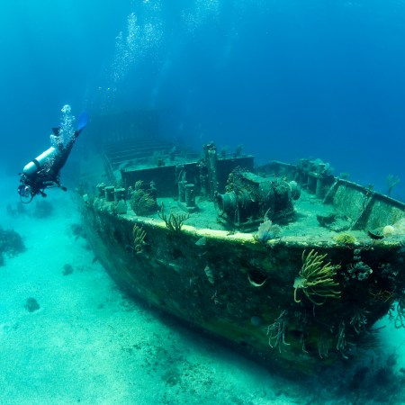 Scuba Diver Exploring a Large Shipwreck in the bahamas. A sunken treasure of booze and gold is planning to be excavated in Lake Michigan soon.