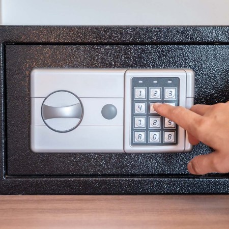 A hand typing in a passcode on a hotel safe box. If you've ever forgotten something in a hotel safe, try this travel hack from TikTok.