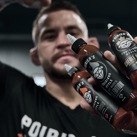 UFC fighter Dustin Poirier holds up his hot sauce line.