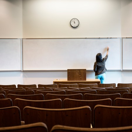 A woman writing on a whiteboard in a lecture hall.