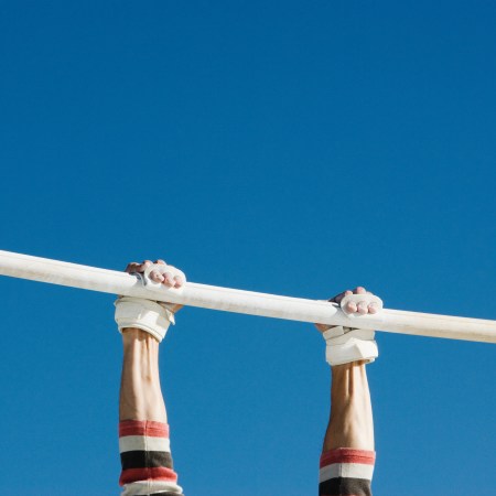 A pair of hands clutching a gymnastics beam. Grip strength may be related to living longer, according to some studies.