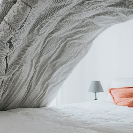 A comforter in motion as someone makes the bed.