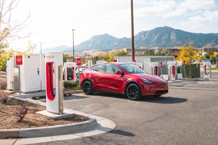 A red Tesla Model Y at a Tesla Supercharger station. Elon Musk said Tesla will open up some of its charging network to other EVs.