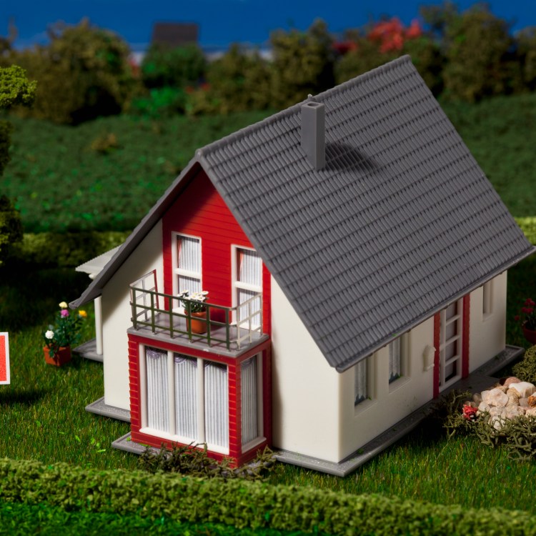 A diorama of a suburban home with a For Sale sign.