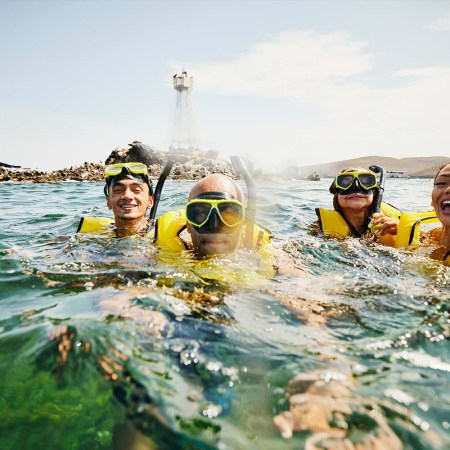 portrait of smiling family on snorkeling tour in tropical ocean while on vacation