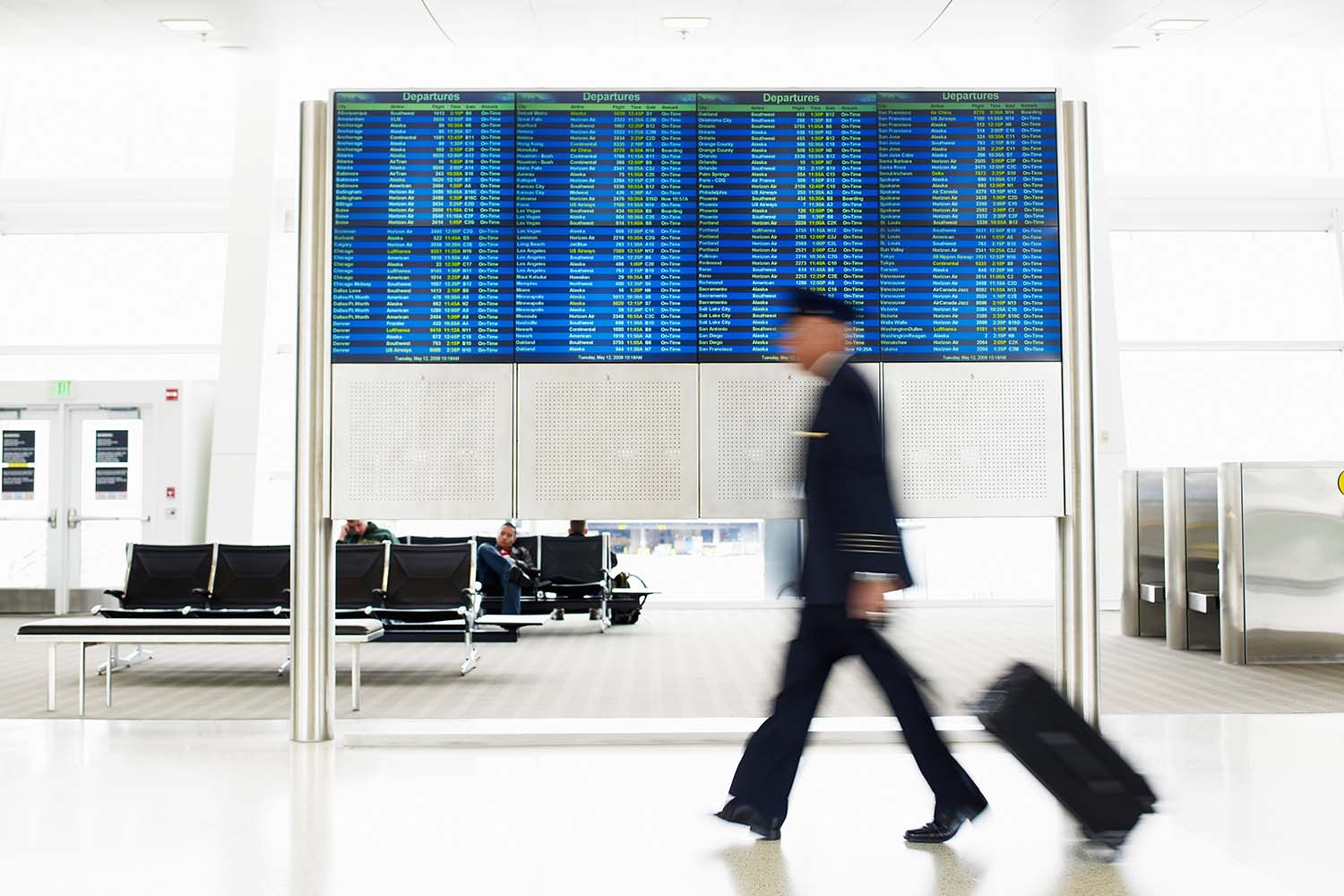 a pilot rolling his bag through the airport