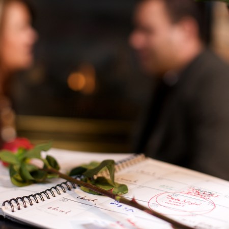 man and woman in background with red rose and calendar showing date night