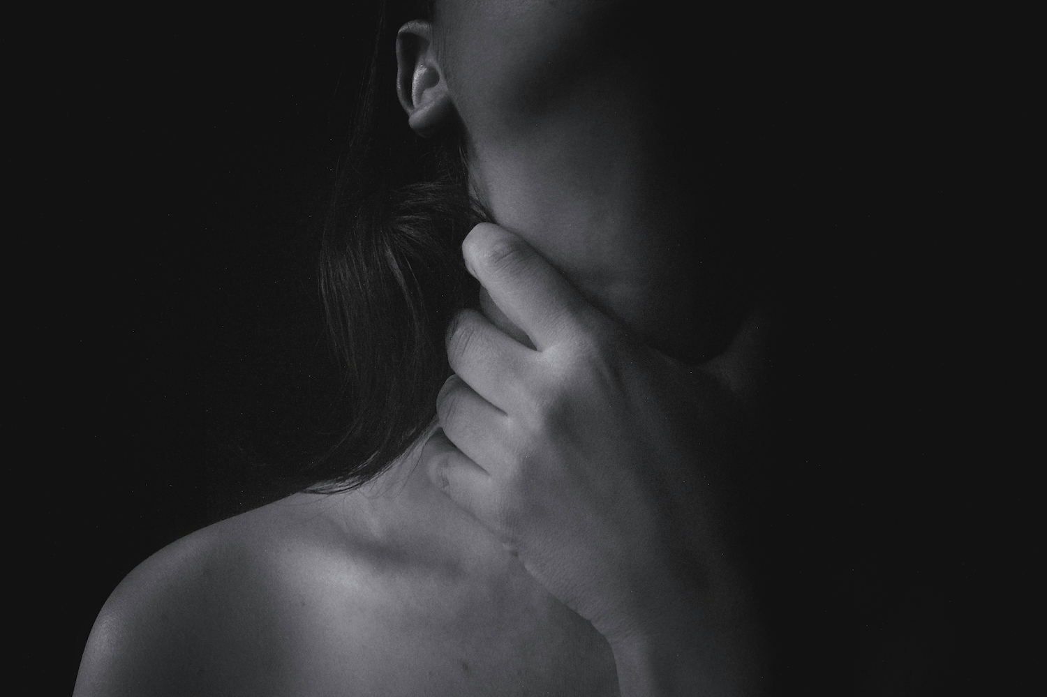 Midsection Of Topless Woman Choking Throat Against Black Background