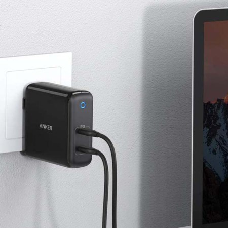 Anker's PowerPort Atom plugged into a wall and charging a laptop. Anker chargers are currently on sale at Amazon