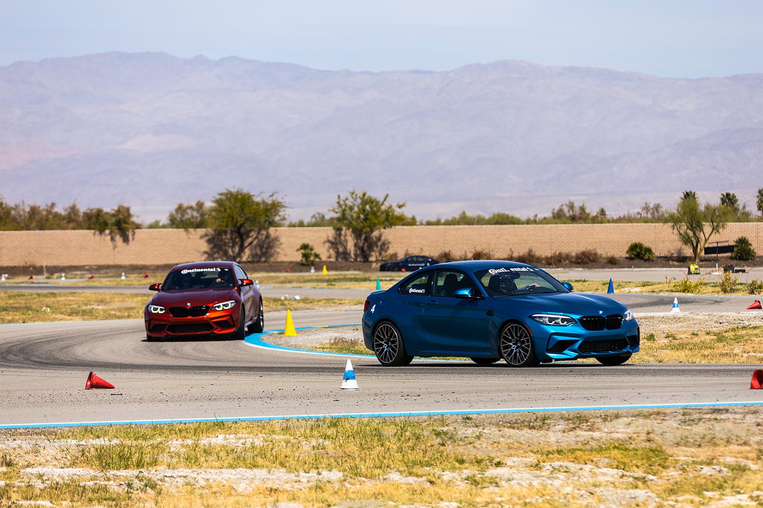 Red and blue BMW M models driving at the BMW Performance Center in Thermal, CA