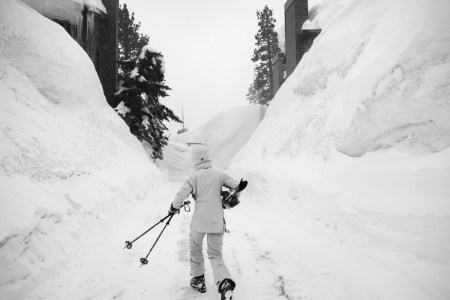 a black and white photo of someone carrying their skis through the Snow