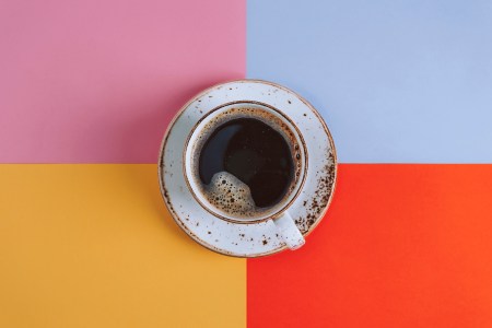 A cup of coffee against a multi-colored background.