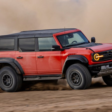 A red Ford Bronco Raptor churning up dust and dirt in the desert. We reviewed the rock-crawling, desert-racing version of Ford's popular Bronco SUV.