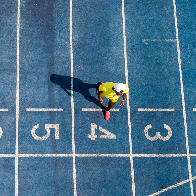 An athlete walking on a blue trrack.