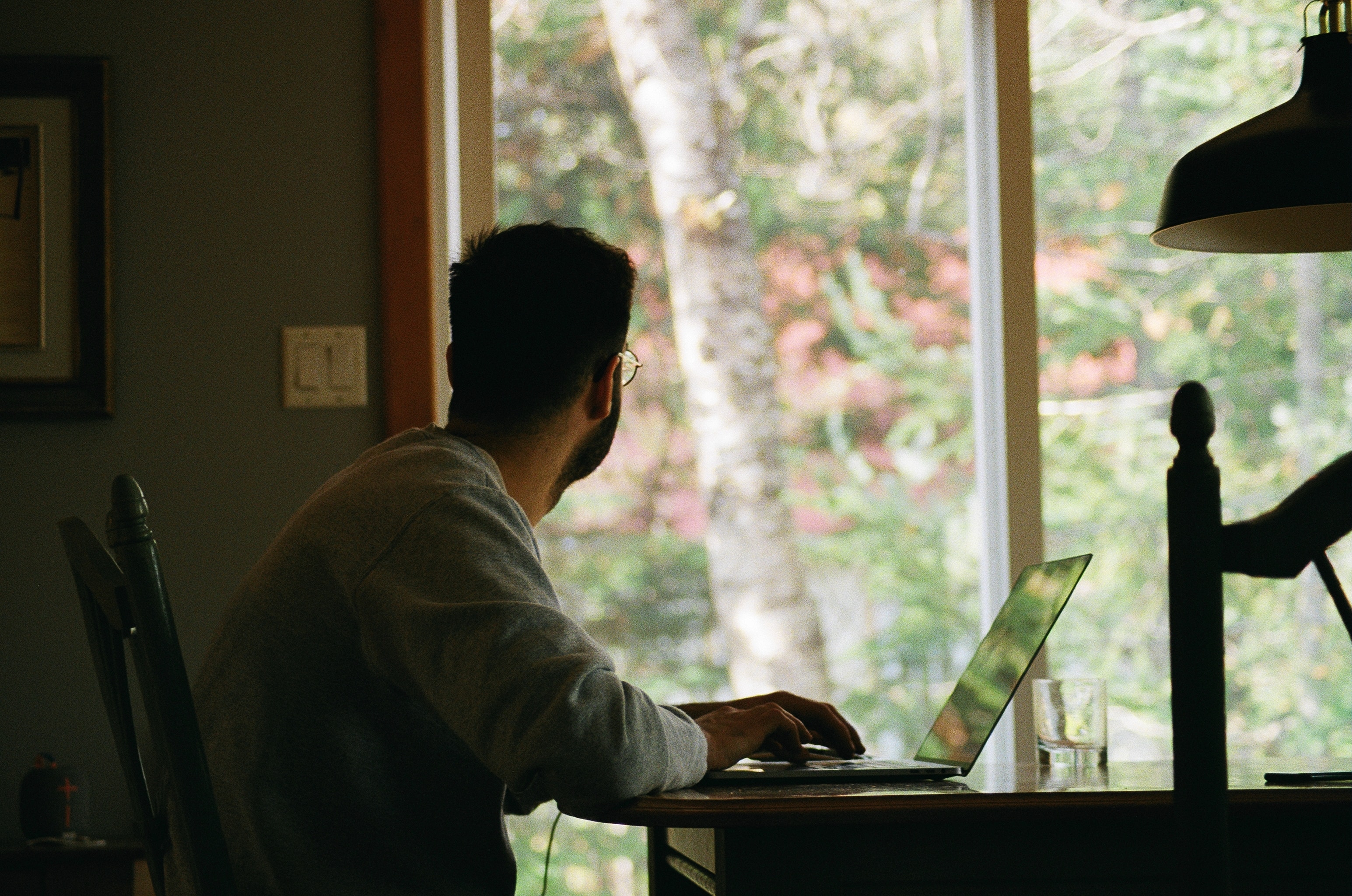 A man at a desk staring out a window.