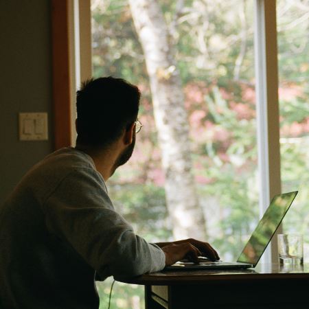 A man at a desk staring out a window.