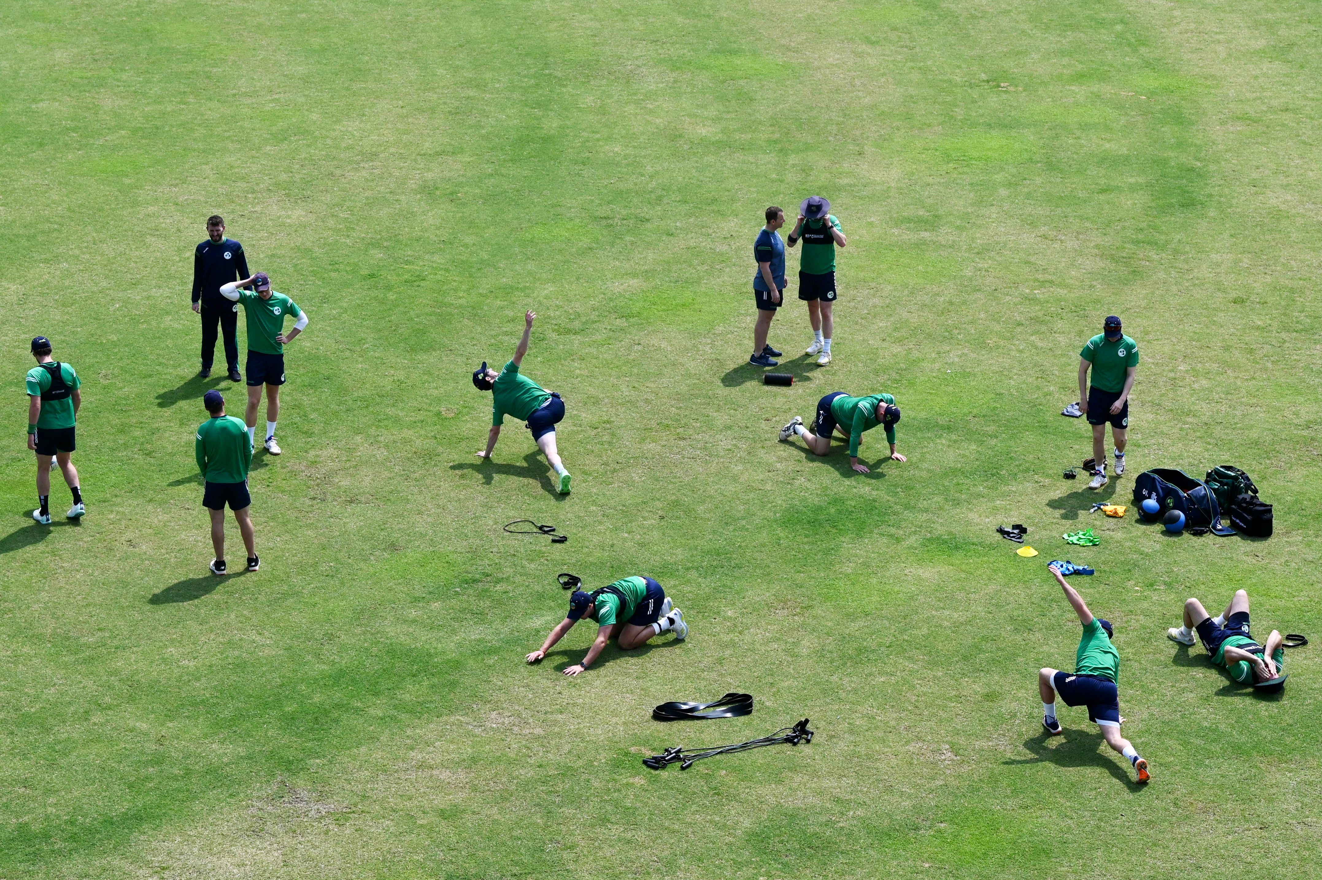 A bunch of cricket players stretching in the sun, from an aerial view.