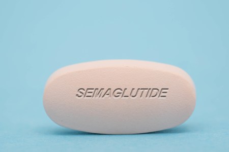 A large semaglutide pill against a blue background.