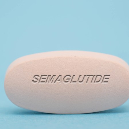 A large semaglutide pill against a blue background.